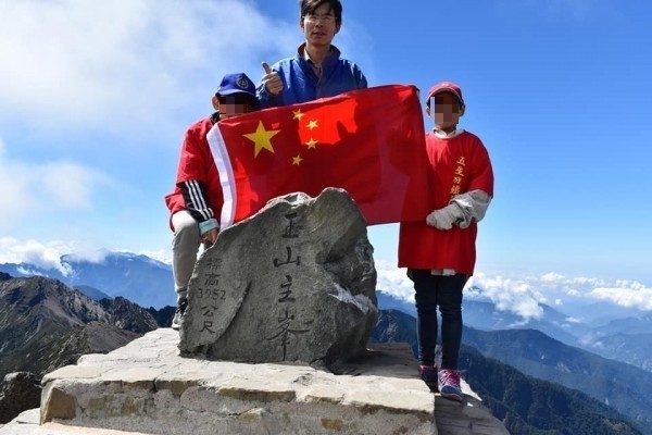 鄭建炘與兒子登頂玉山主峰，持五星旗、唱中華人民共和國歌。（圖擷取自鄭建炘臉書）