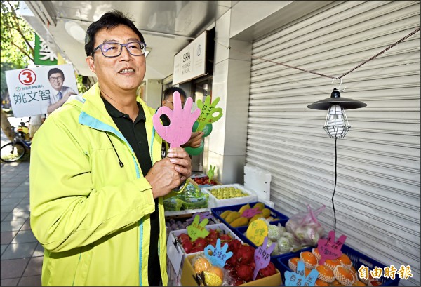 民進黨台北市長候選人姚文智昨在民生社區徒步掃街拜票，拿起水果攤位代表自己3號OK的牌子。（記者簡榮豐攝）