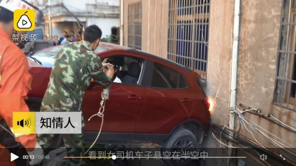 中國江西一名女子疑似錯把油門當煞車，轎車懸在深達5公尺的深溝上，車尾則抵在一家平房的牆壁上，車子隨時都有可能掉落。（圖擷取自梨視頻）