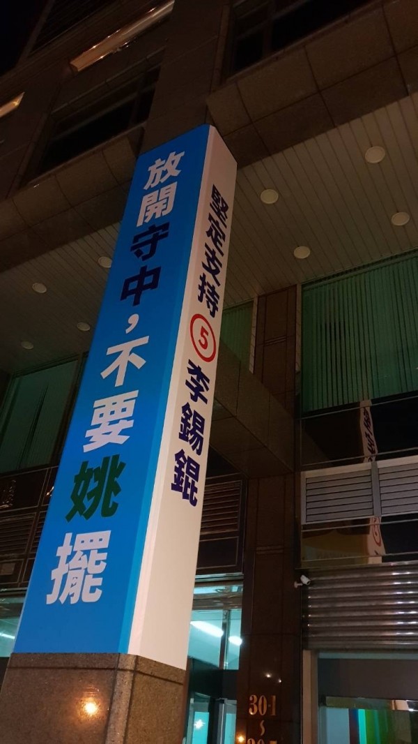 李錫錕喊出新口號「放開守中、不再姚擺」已掛在競選總部、姚文智辦公室樓下。（圖：李錫錕競總提供）