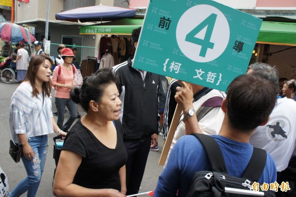 柯媽上午赴文山區興德路市場拜票，遭一名黑衣婦人緊隨抗議。（記者黃建豪攝）