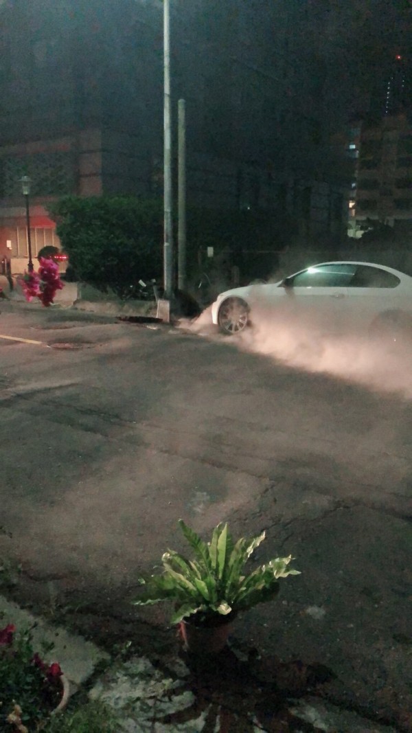 高市前金區馬路人孔蓋氣爆冒煙，波及一輛BMW。（記者黃良傑翻攝）