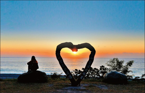 太陽從海平面上突破雲層露出光芒，利用華源海灣的愛心地景可拍出獨特的日出穿心紀念照。（記者許麗娟／攝影）