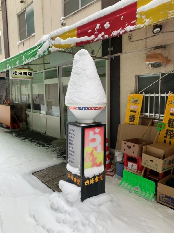 日本一名網友在推特上貼出1張拉麵店招牌的照片，但因為積雪的關係，拉麵店外的拉麵模型，看起來就像是一碗刨冰模型。（圖擷取自推特）