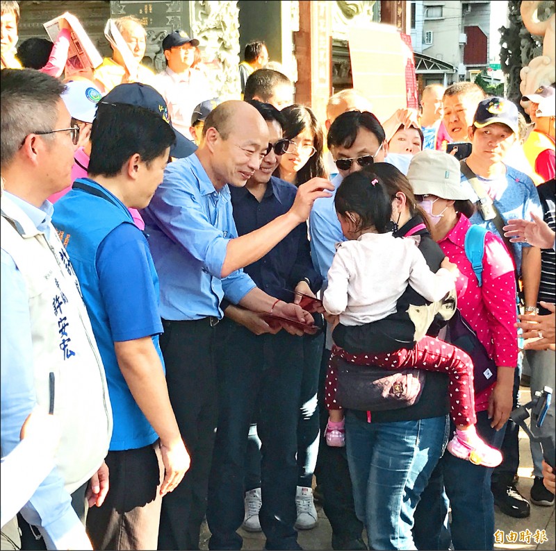 高雄市長韓國瑜昨天到鳥松區瑯環宮發放福袋，看到幼童開心摸頭賀年。（記者洪臣宏攝）