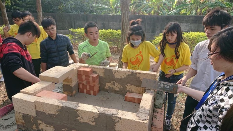資訊志工與嘉田社區國高中生共同砌起屬於社區的「嘉冬窯」。（崑山科大提供）