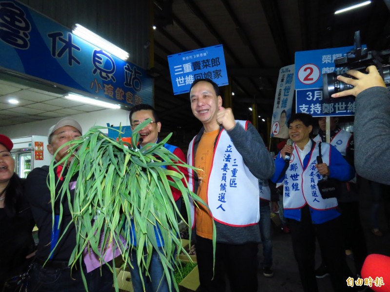 前新北市長朱立倫（中）今天清晨陪同國民黨三重立委補選候選人鄭世維（右），至三重果菜批發市場拜票，攤商熱情送上象徵「凍蒜」的蒜頭。（記者陳心瑜攝）