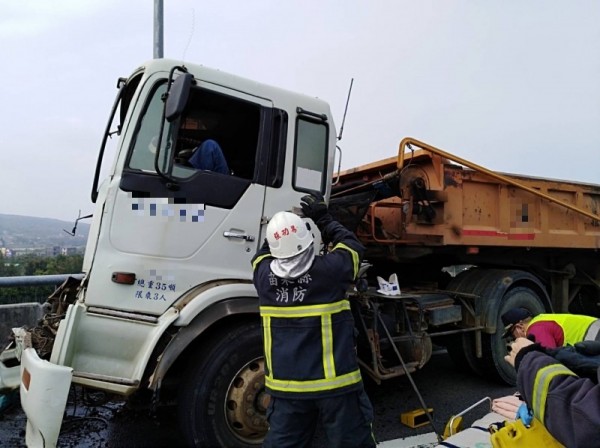 苗栗縣中山高速公路銅鑼交流道往銅鑼科學園區匝道口，發生2輛砂石車追撞意外，後方駕駛受困駕駛座，經消防隊員使用翹棒、破壞器材將傷者救出送醫。（記者彭健禮翻攝）