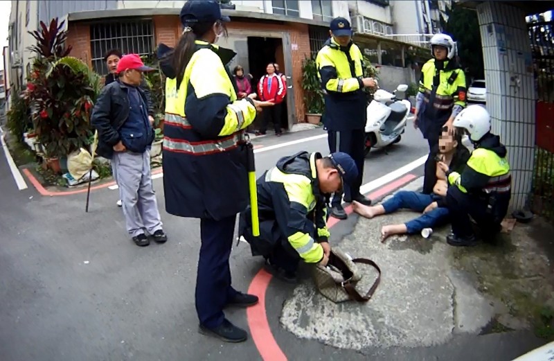 遭通緝王男被警逮下，怕被查出身分，竟賴坐在地上裝暈、擠眉弄眼。（記者許倬勛翻攝）