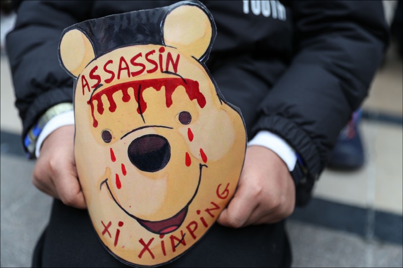 本月24日抗議習近平訪法的遊行上，一名法國示威者拿著小熊維尼的面具，上面寫著「殺人犯習近平」。（法新社檔案照）