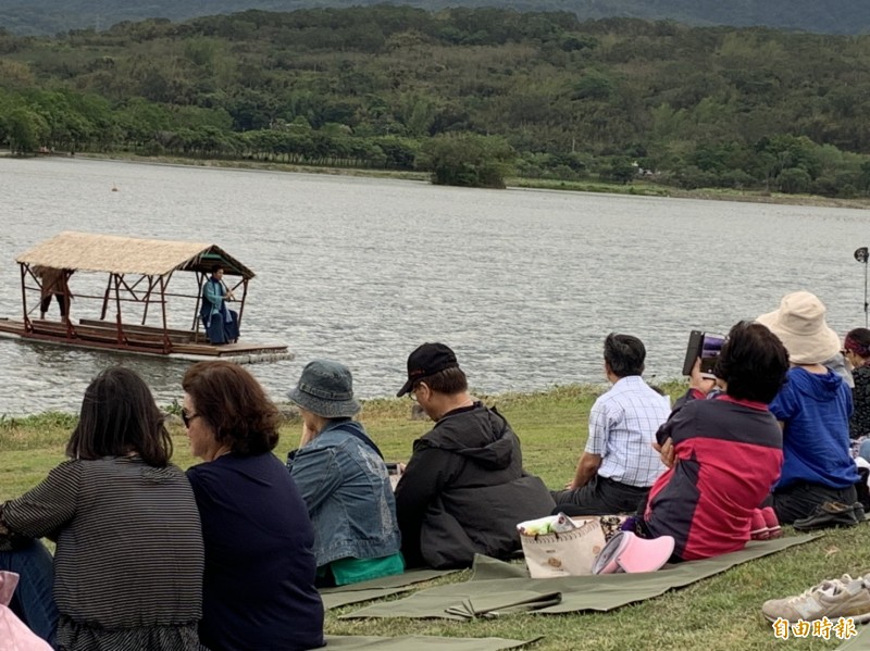 民眾席地聆聽心心南管樂坊團員乘著竹筏在湖面上吹奏，直呼好享受。（記者陳賢義攝）