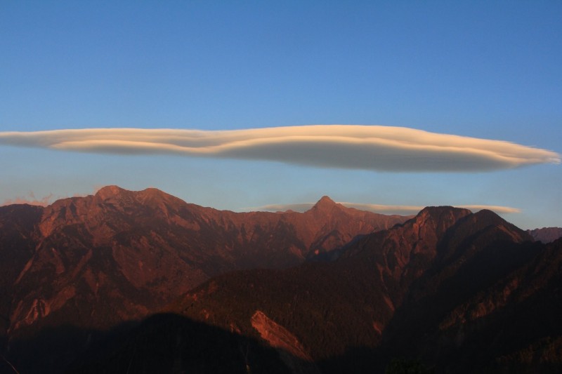 玉山主群峰上月底出現大跨度斗笠雲，扁平雲團彷彿飛碟，美得讓人驚豔。圖中偏右，尖峰為玉山主峰。（玉管處提供）