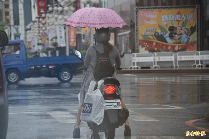 手撐傘、腳穿矮子樂，女騎士騎機車在市區展「特技」，讓人都驚嘆。（記者葉永騫攝）