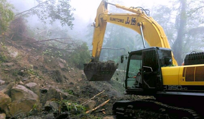 公路總局信義工務段派出挖土機、大卡車等機具，冒雨清除新中橫觀山路段落石情形。（記者謝介裕翻攝）