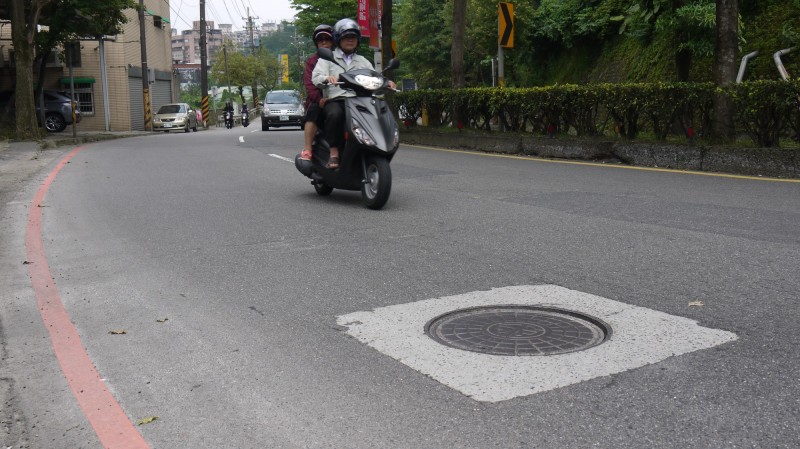 民眾反映，基隆市基金一路路段的人孔蓋，因天雨濕滑，常有機車騎士摔車，險象環生。（立委蔡適應服務處提供）