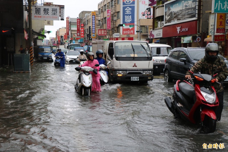 永康大灣路一帶積淹水，騎士只好牽車經過。（記者萬于甄攝）