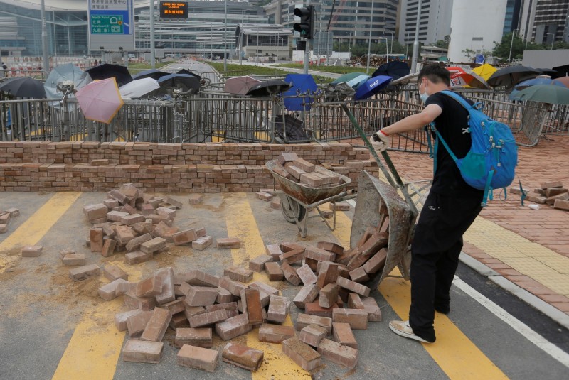 為了鞏固防線，有抗議民眾就地取材，直接將人行道磚頭一塊塊鑿起，砌成城牆。（（路透）