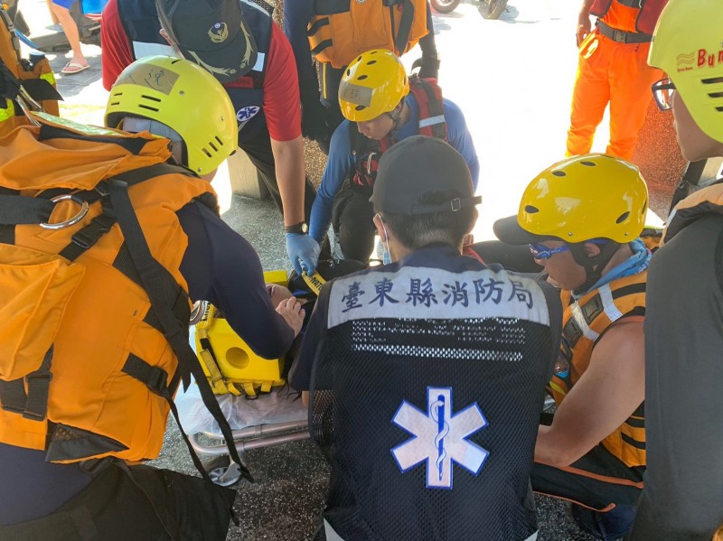 海巡人員及警消合力將昏迷的鄧姓女潛水客救上岸，並緊急送醫。（記者王秀亭翻攝）