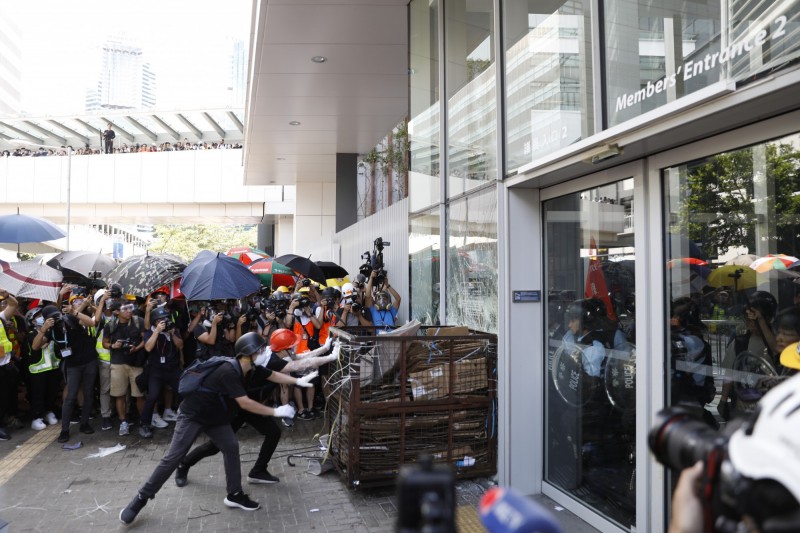 香港示威民眾試圖撞破立法會大門，香港鎮暴警察舉起紅旗警告。（彭博）