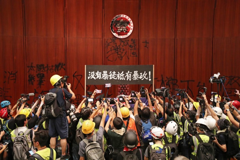 今日「反送中」港民衝進立法會，示威者將主席台後方牆上的香港特別行政區區徽噴上黑漆，遮蔽了「中華人民共和國」字樣和紫荊花圖案。（歐新社）