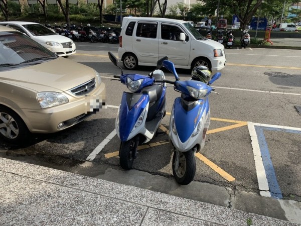 2輛機車違停在2個汽車停車格中間。（賴先生提供）