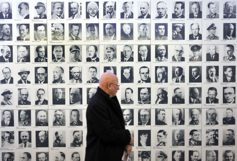 有名男子在德國抵抗運動紀念中心，他路過的牆面上貼著當年試圖暗殺希特勒的部分官員肖像。（法新社，資料照）