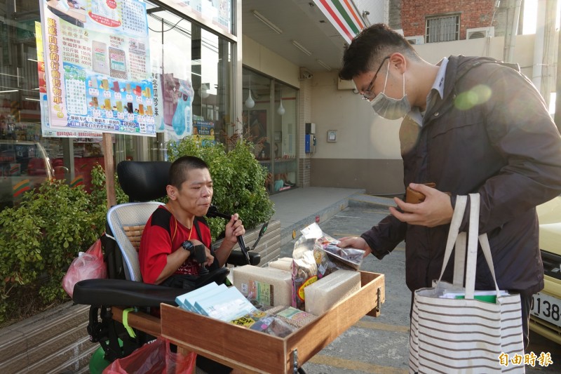 慢飛天使黃囿鈞賣自己的書、還有友善米與朋友家的產品，路過民眾自行挑選，連付費都是自己找零。（記者劉曉欣攝）