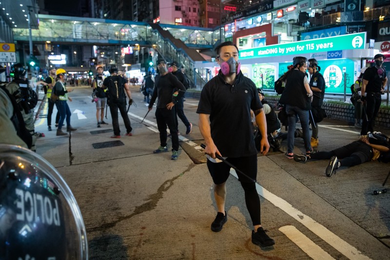 香港銅鑼灣11日晚間出現多名打扮狀似示威者，但手持伸縮警棍的黑衣人，被認為是香港警方假扮示威者，從中挑起衝突。（彭博）