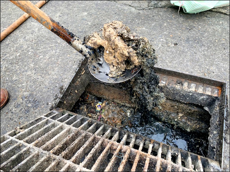 北港鎮公所檢查發現排水溝內卡了許多結塊油垢影響水流，是造成市區淹水的禍首之一。（記者黃淑莉翻攝）