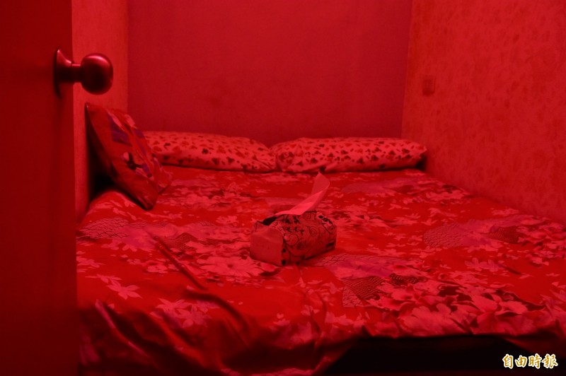 點著紅燈的小隔間，床位大小僅容得下兩個人。（記者張議晨攝）