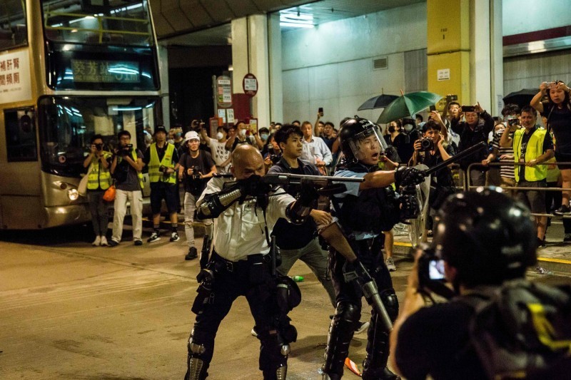 香港葵涌警署7月30日被示威者包圍，當時「光頭警長」劉澤基（見圖中）持霰彈槍瞄準群眾引發眾怒，卻獲得中國網民大力推崇，事後已獲邀出席中國國慶相關活動，近日中國中央電視台還大力吹捧。（法新社資料照）