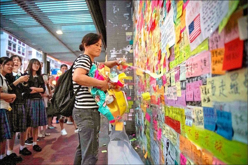 香港一名婦人十六日在炮台山撕毀當地的連儂牆。（法新社）