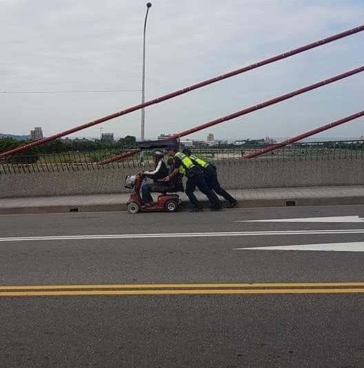 太平分局坪林派出所的警員張貴程和簡延圳，今天在路上合力推電動車沒電的老翁回家，暖心舉動遭民眾拍照po網。（記者陳建志翻攝「我是太平人」）