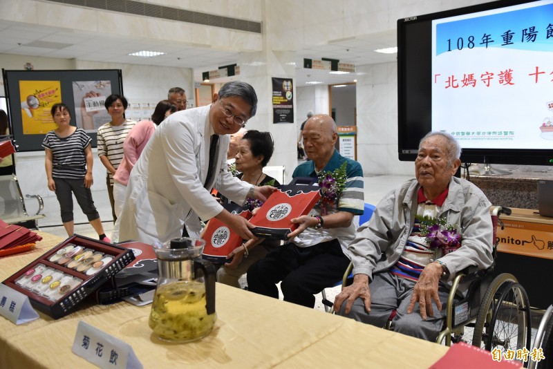 中國醫藥大學附設北港醫院今天舉辦健康重陽活動，院長吳錫金贈送90歲長輩百壽糕。（記者黃淑莉攝）