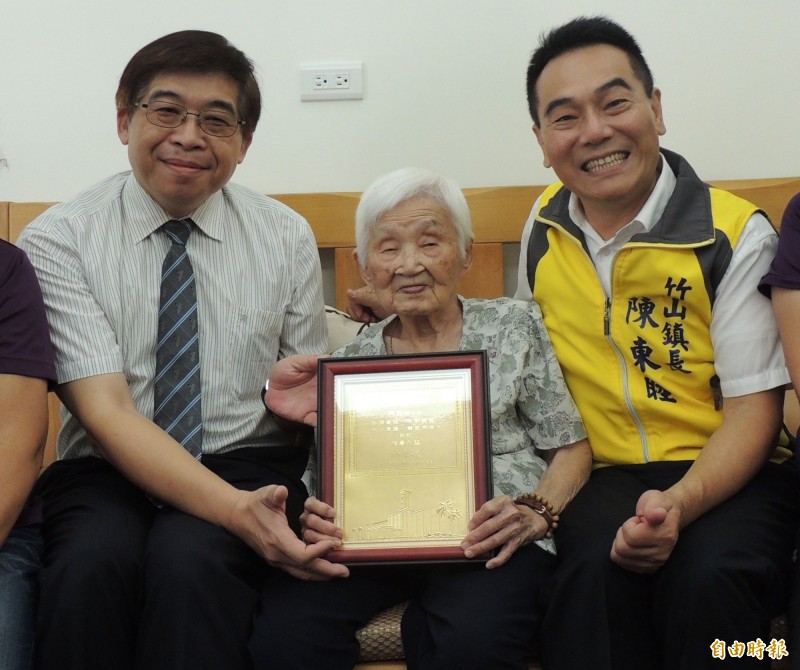 南投縣政府祕書長洪瑞智（左）、竹山鎮長陳東睦（右）拜訪竹山百歲人瑞陳劉柚（中），祝賀老人家健康「呷百二」。（記者劉濱銓攝）