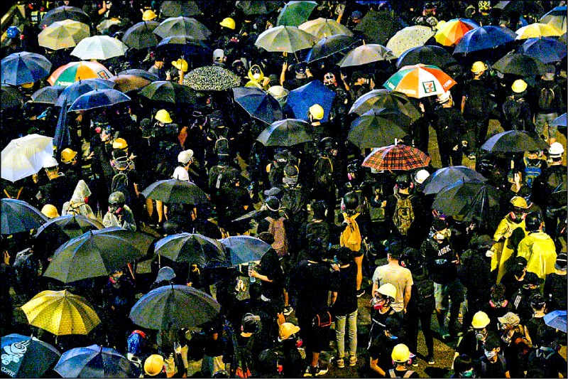 「雨傘運動」五週年，香港政府總部外又發生警民衝突，示威者以傘陣對抗水砲車。（法新社）