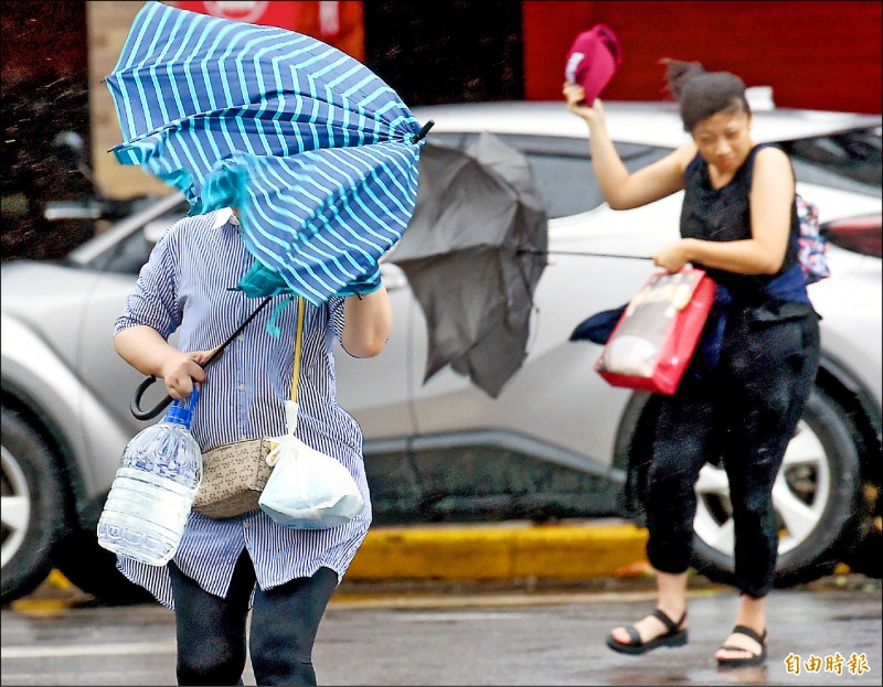 米塔颱風襲台，台北市區昨日下午風雨逐漸增強，撐傘的行人難以招架。（記者朱沛雄攝）