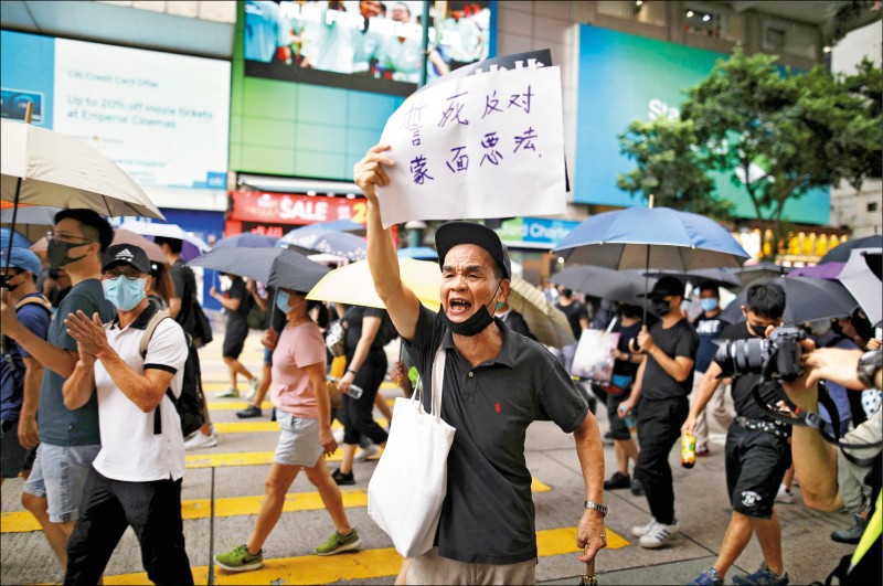 示威者高舉「誓死反對蒙面惡法」標語。（路透）