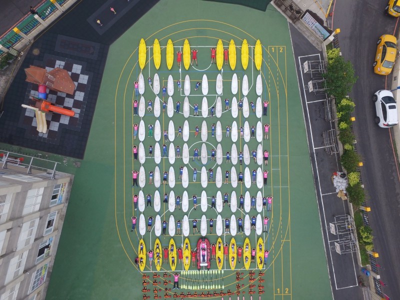 野柳國小近日趕上開箱文風潮，動員全校100多名師生將100多艘獨木舟搬上操場，學生再躺在上面與獨木舟合拍。（野柳國小提供）
