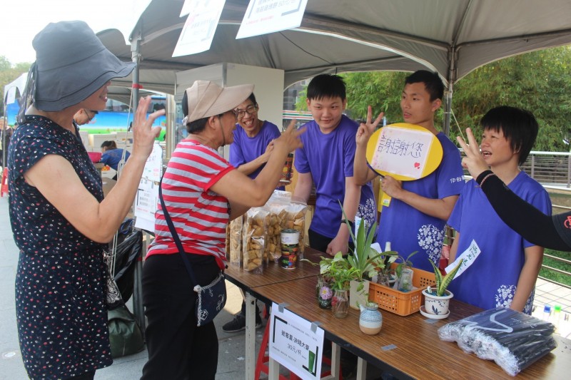 伊甸身障青年鄭景儒（右2）首次擔任小店長，親手製作手拿牌感謝民眾。（伊甸基金會提供）