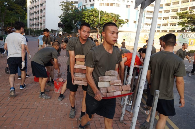 中國人民解放軍駐港部隊16日「自發」出營區協助清路障。（法新社）