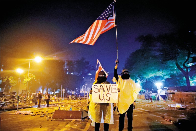 香港理工大學外的示威者，18日在警方發佈最後通牒後，高舉美國和英國國旗，及寫有「救救我們」的標語。（美聯社）