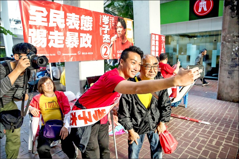 香港區議會選舉今登場，外界高度關注議席消長，參選沙田瀝源區的泛民主派「民間人權陣線」（民陣）召集人岑子杰，和支持者自拍。（彭博）