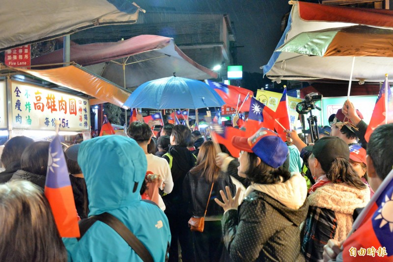 韓粉手持國旗站在廟埕前的夜市街道上，因逛街的遊客走不過去，還有商家請停在攤前的韓粉讓路給客人走。（記者許麗娟攝）