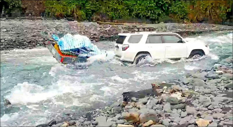 四輪傳動車冒險渡溪紮營，卻意外受困，警方在旁戒護，所幸7部車在水退後自行脫困。（記者張議晨翻攝）