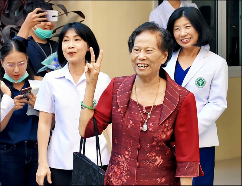 感染武漢肺炎的泰國七十三歲阿嬤尚雲（Jaimuay Sae-Ung，中），四日痊癒出院，開心地在佛統府（Nakhon Pathom）的佛統醫院前比出勝利手勢。尚雲阿嬤是泰國當地第一個確診的病例，與病魔對抗一個月後終於康復。她去年耶誕節疫情尚未爆發前和家人到武漢旅遊，不料回到家後感到身體不適，就醫後被判定為泰國武漢肺炎的首個確診病例。（歐新社）