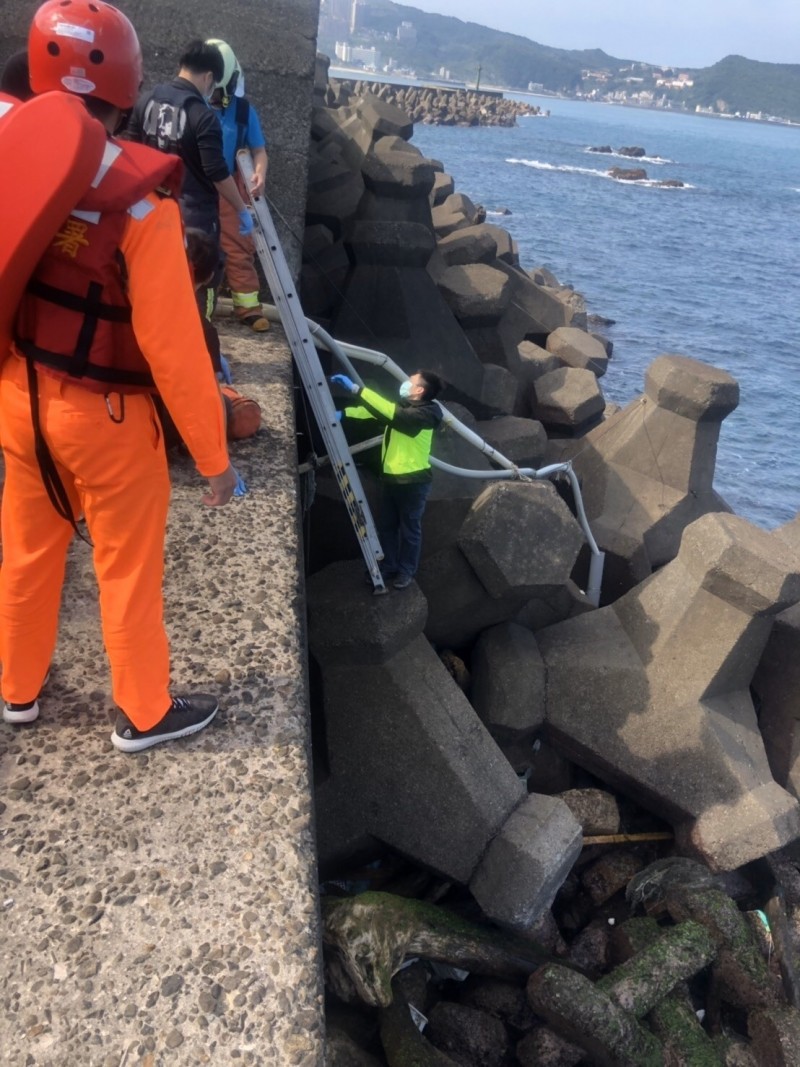 58歲楊姓釣客今天被發現卡在瑪鋉漁港安檢所留置室旁堤防與消波塊間，消防人員救出時已無氣息。（記者林嘉東翻攝）