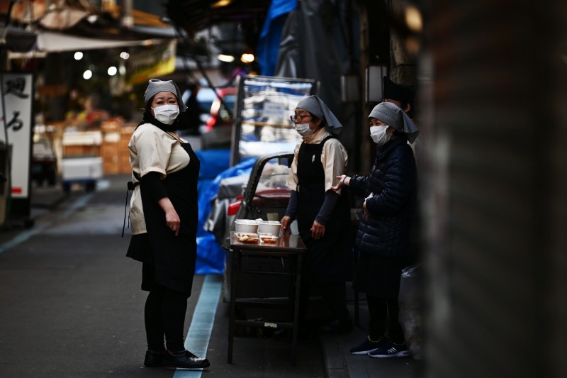 日本疫情上升，居住在東京的民眾戴上口罩防疫。（法新社）