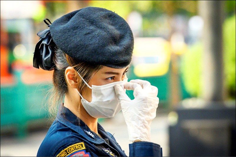 泰國女警一日在曼谷一場反政府示威活動中戴上口罩，以防染病。（法新社）