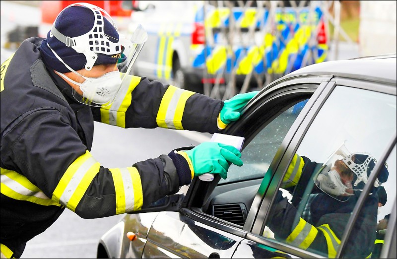 穿戴防護裝備的捷克特種警察，九日在捷克和德國交界的健檢站檢測駕駛人的體溫。（法新社）